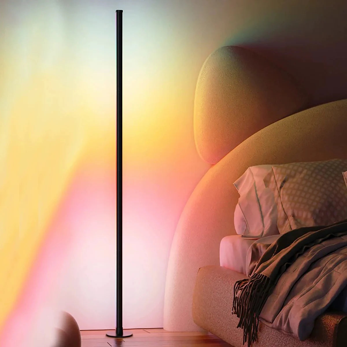 Slim RGB corner floor lamp lighting a wall in color behind a gaming desk