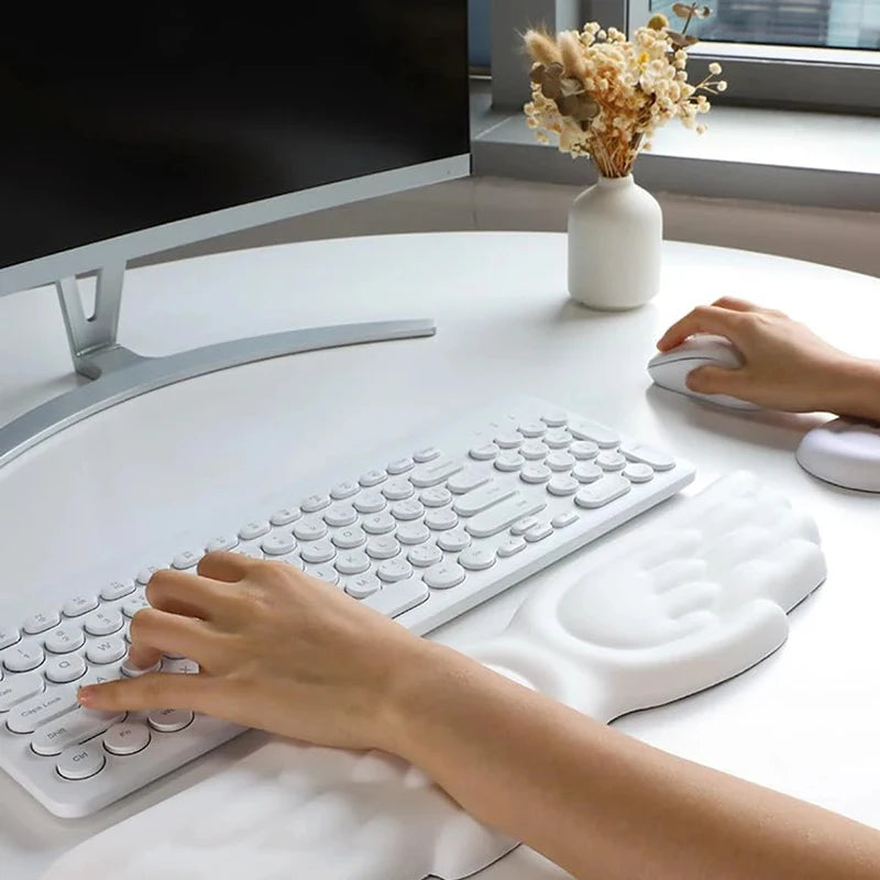 Hands typing on a white keyboard with an angel wing wrist rest in front