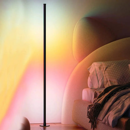 Slim RGB corner floor lamp lighting a wall in color behind a gaming desk