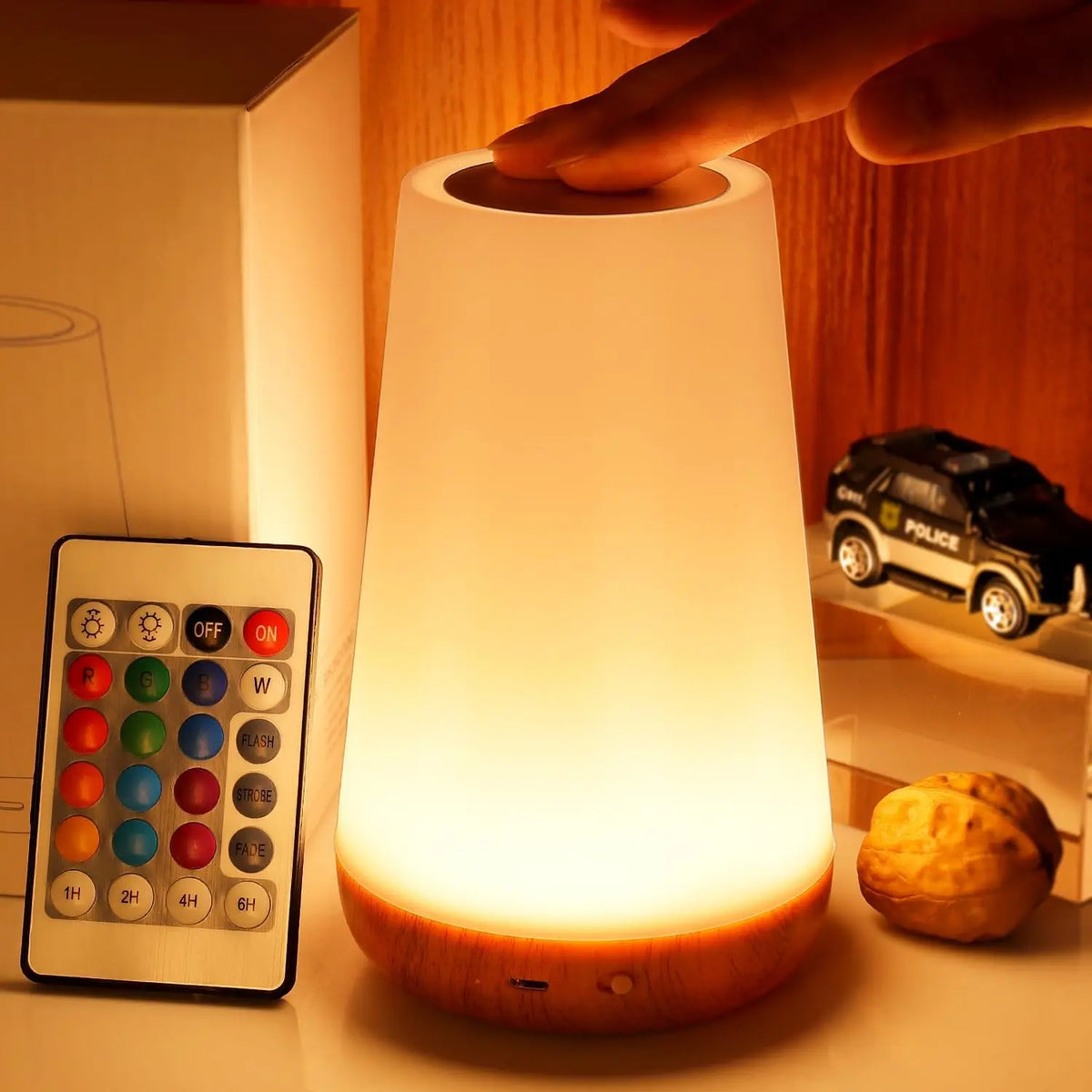 Rechargeable RGB night lamp glowing in color beside its remote control