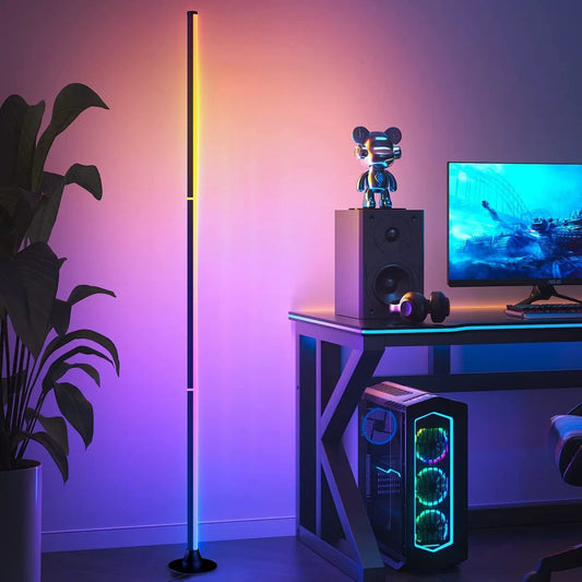 Slim RGB corner floor lamp lighting a wall in color behind a gaming desk
