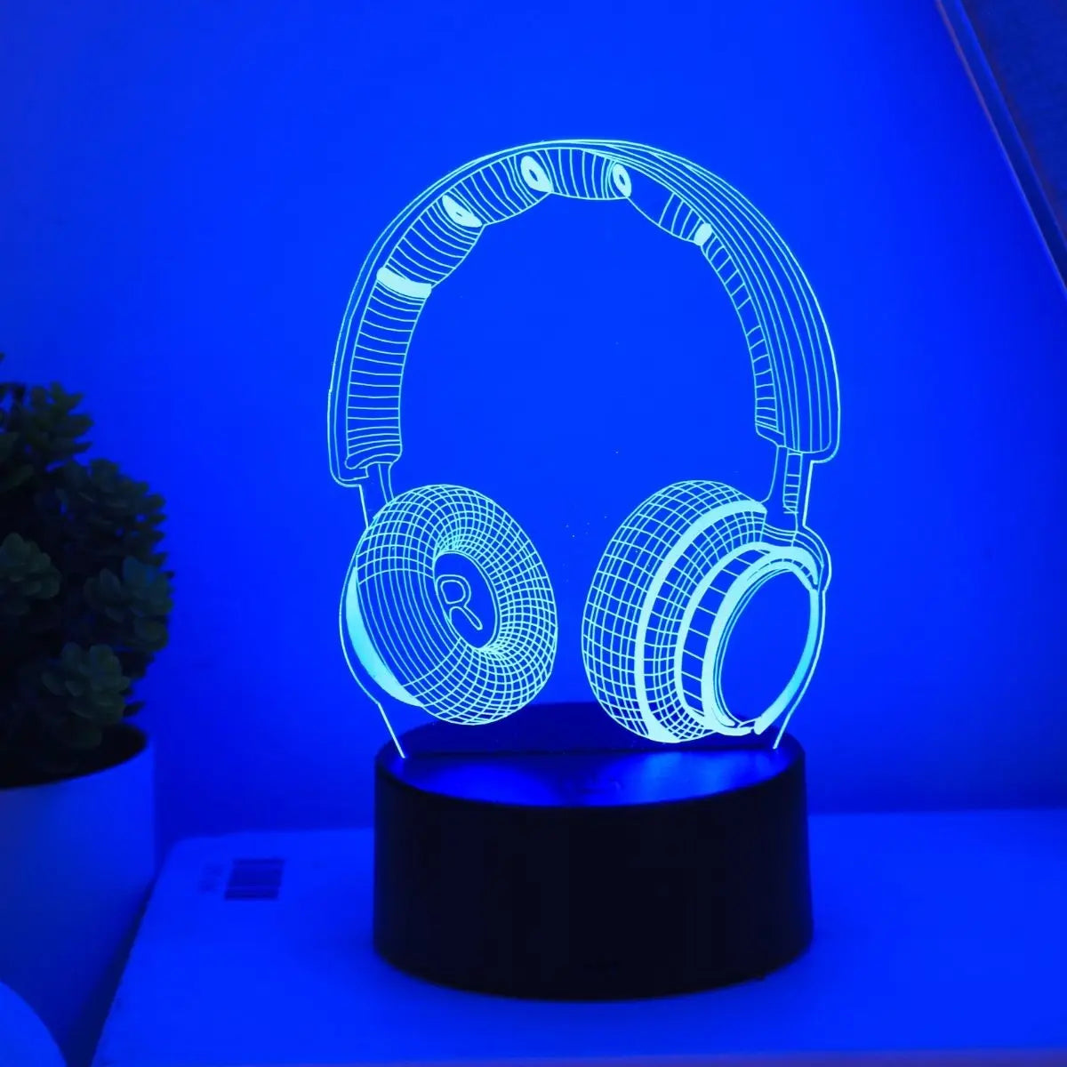 Headphones night light glowing blue on a lit base in a dark room